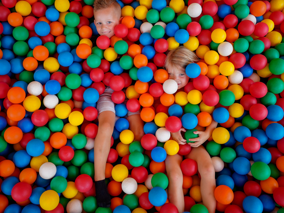 Twee kinderen spelen verstoppertje in een grote, kleurrijke ballenbak in het overdekte speelparadijs van Wunderland Kalkar.