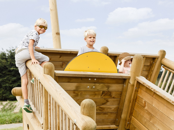 Twee jongens spelen als piraten op het houten speelschip in de buitenspeeltuin van het vakantiepark in Zeewolde.