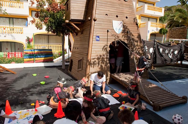 Een groep kinderen is druk aan het knutselen op de grond tijdens een activiteit van de kinderclub bij Royal Son Bou, begeleid door het animatieteam.