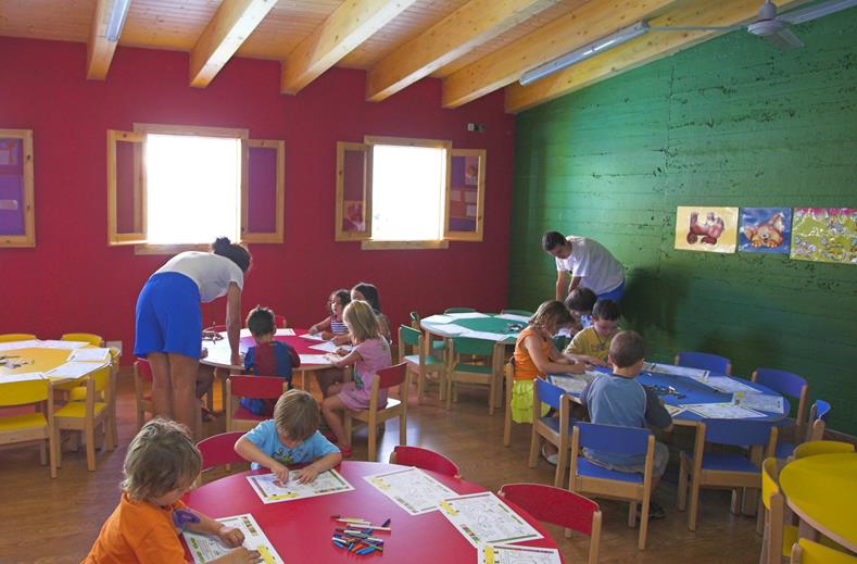 Kinderen zitten aan tafeltjes te kleuren en knutselen onder begeleiding van het animatieteam in de kidsclub van Royal Son Bou.