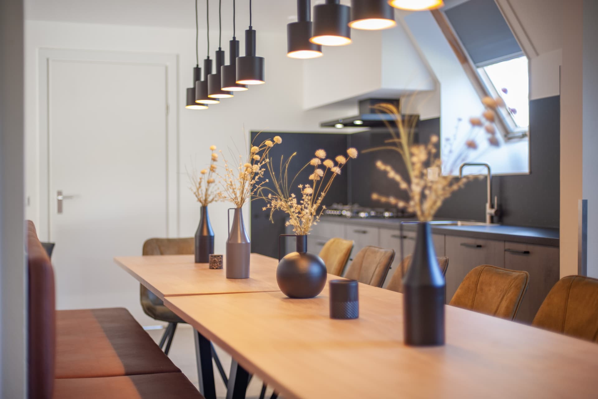 Moderne eethoek met lange houten tafel en open keuken in een accommodatie op De Katjeskelder.