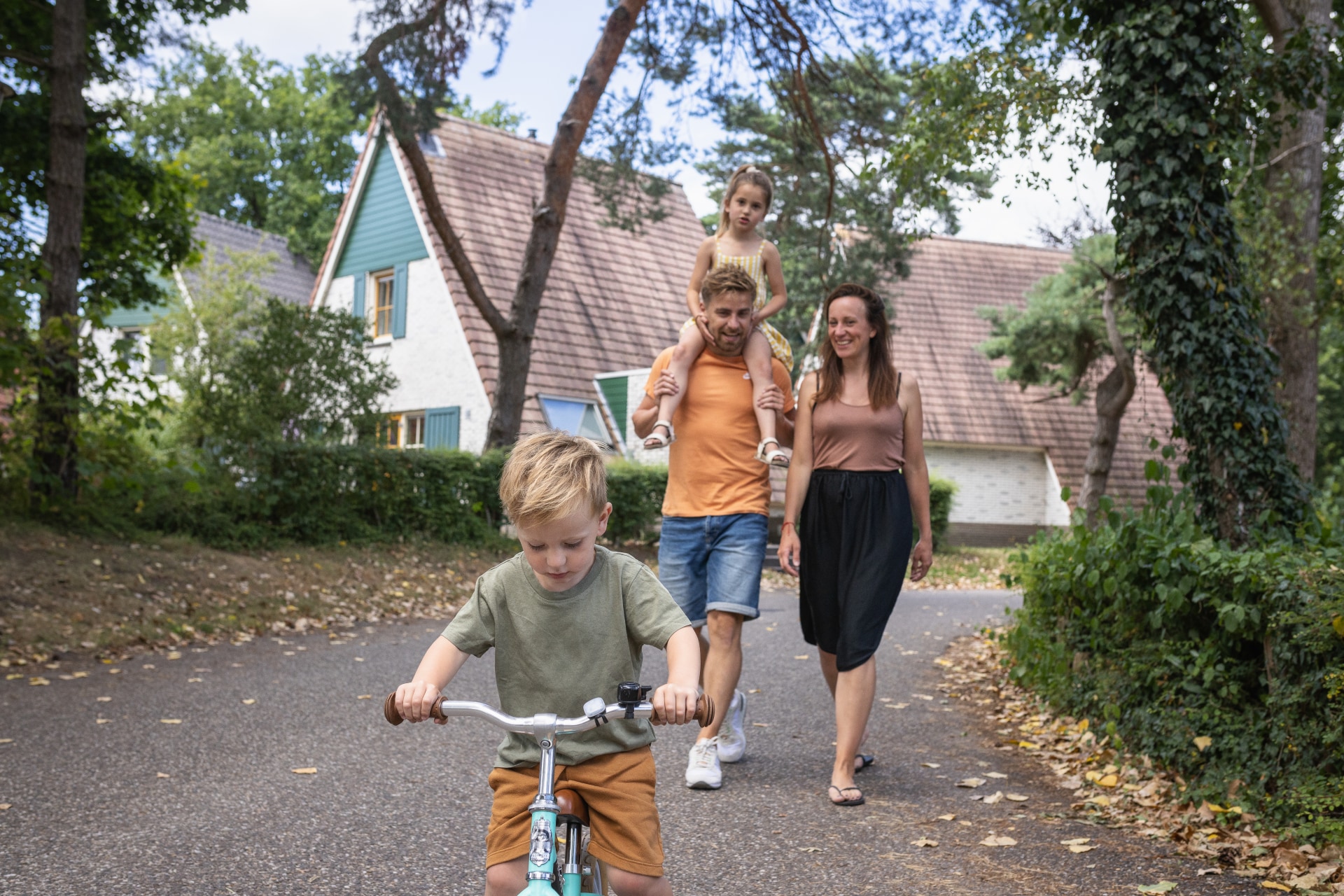 Gezin met jonge kinderen wandelt en fietst over een pad op vakantiepark De Katjeskelder.