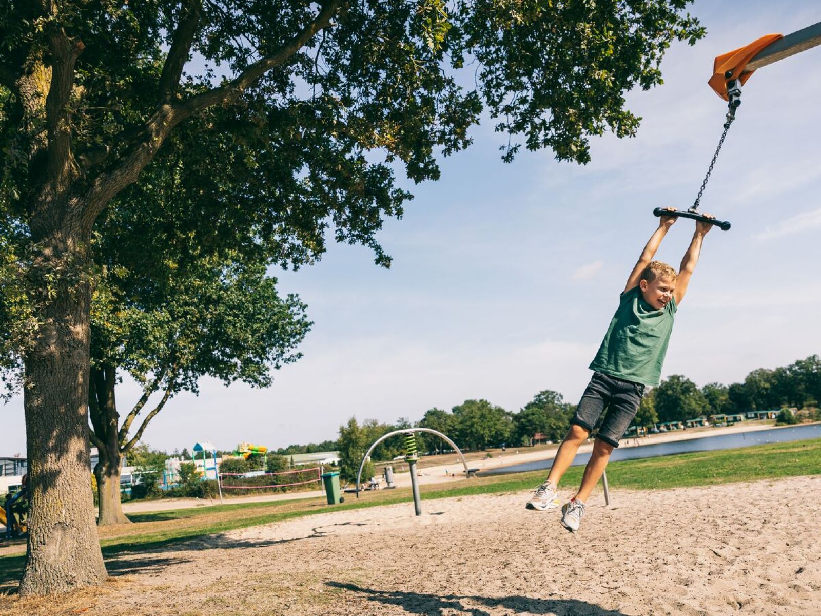 Jongen zoeft met hoge snelheid aan de kabelbaan over het zandstrand van Camping de Schatberg.