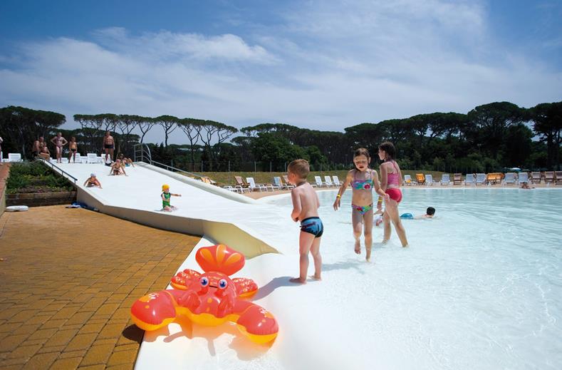 Kinderen spelen op de zachte, veilige bodem van het lagune zwembad op de kindvriendelijke camping Park Albatros in Toscane, Italië.