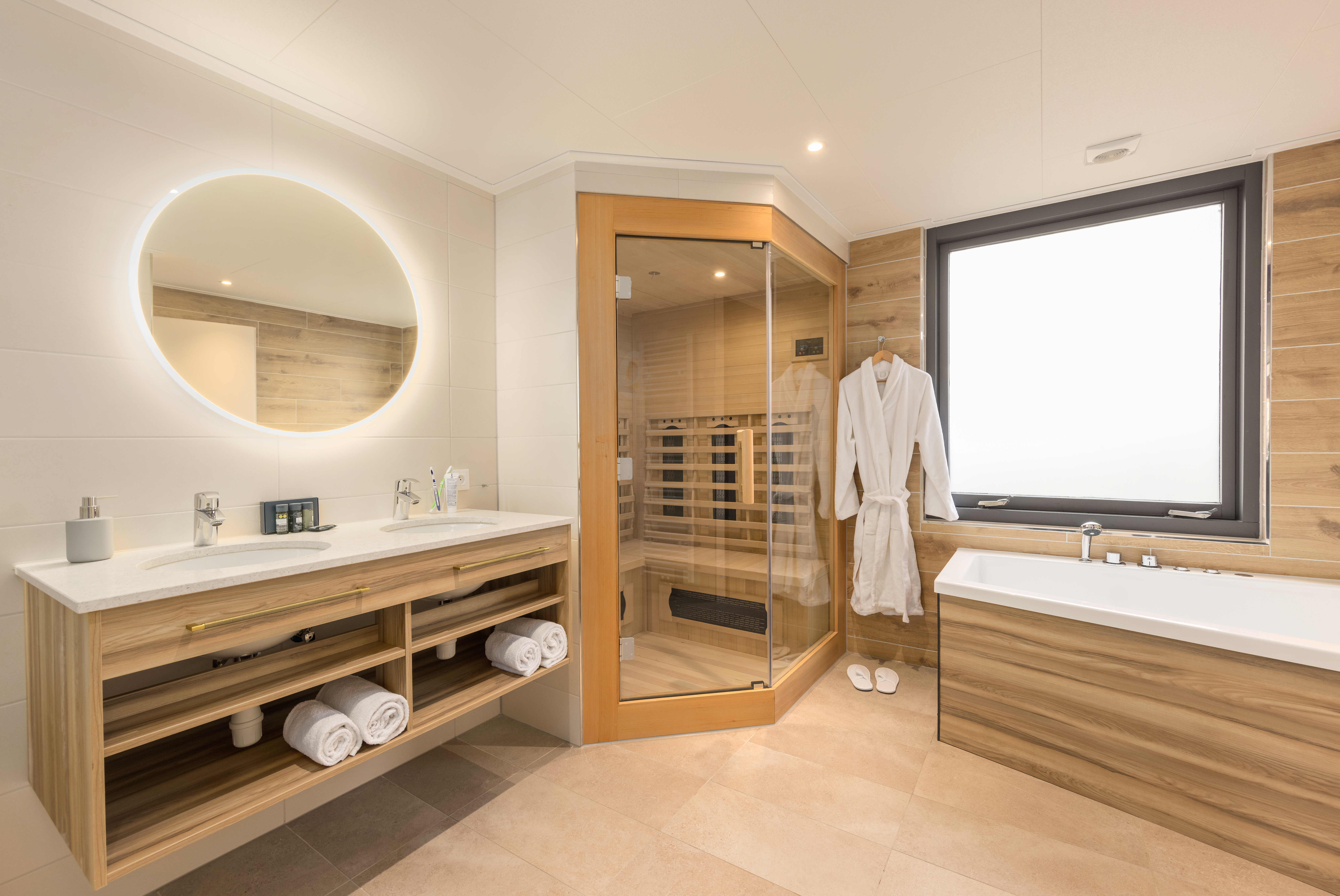 De luxe wellness-badkamer in een VIP cottage bij Center Parcs Erperheide, voorzien van een Finse sauna, een bubbelbad en een dubbele wastafel.