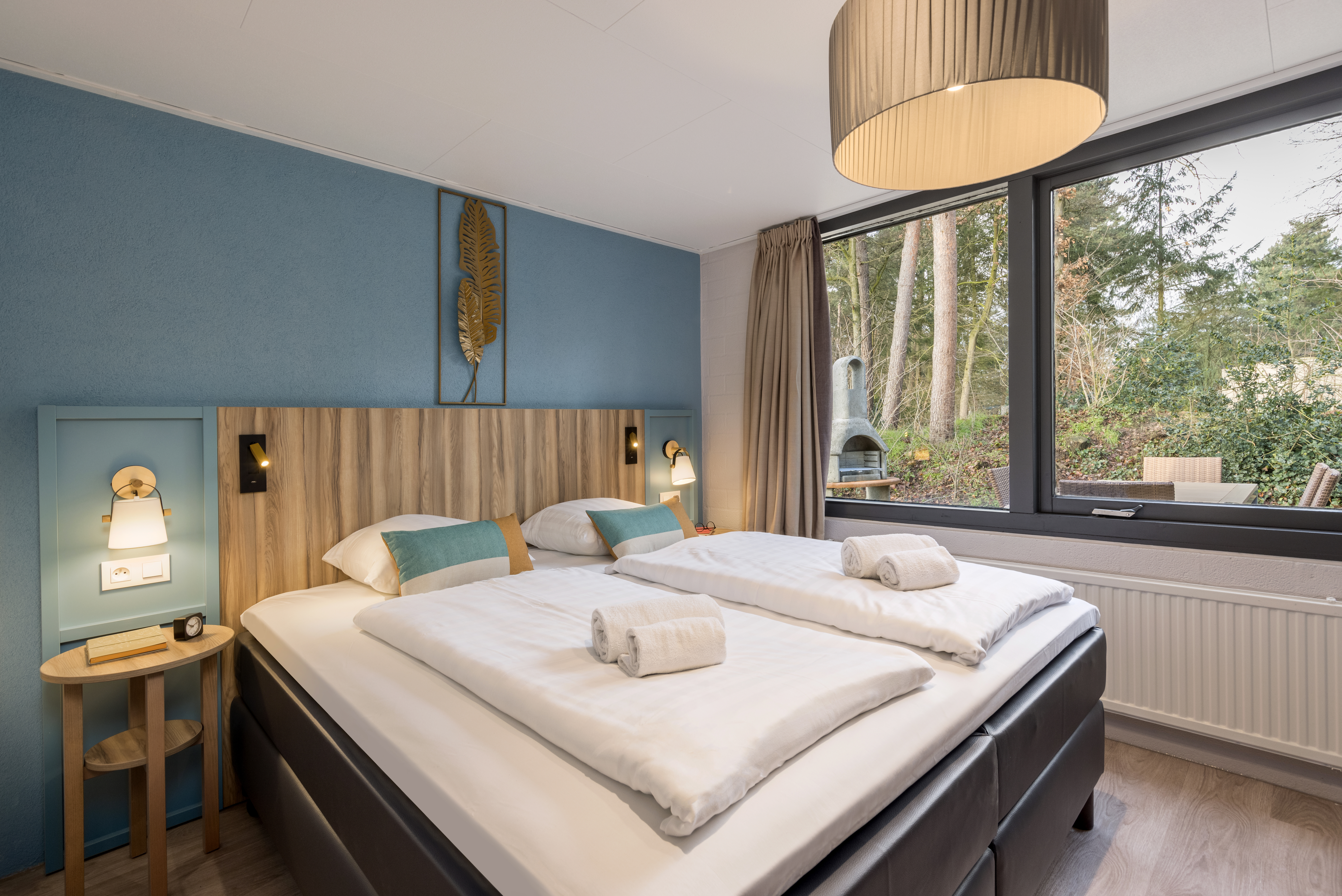 De stijlvolle slaapkamer van een vernieuwde cottage bij Center Parcs Erperheide, met een comfortabel opgemaakt tweepersoonsbed en uitzicht op het bos.
