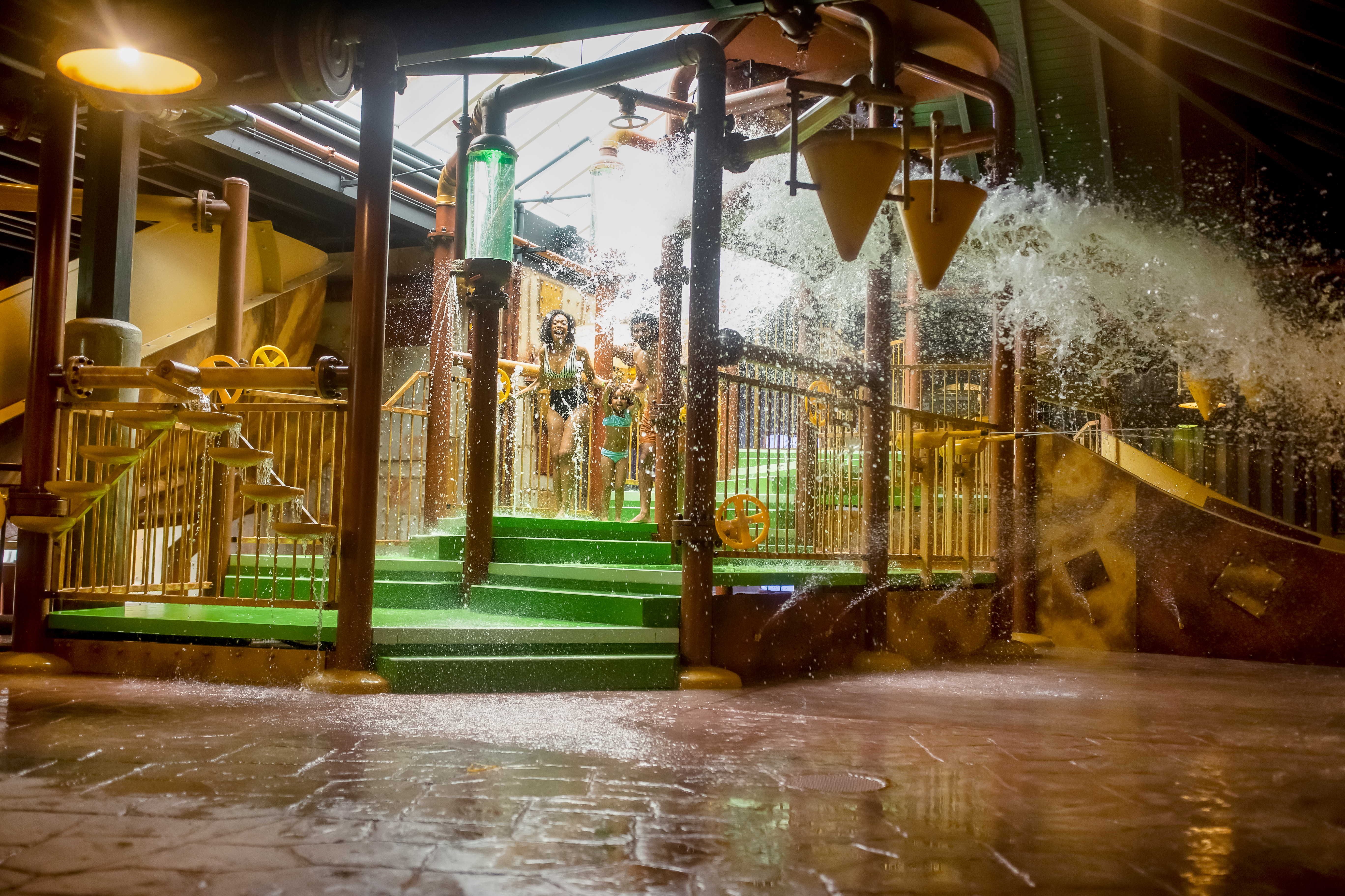 Kinderen spelen onder grote omkiepende emmers met water in het Water Playhouse van de Aqua Mundo bij Center Parcs Erperheide.