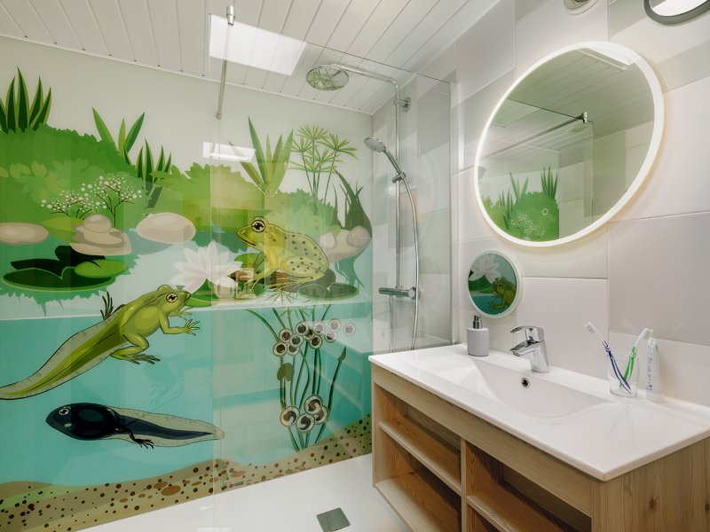 Een vrolijke badkamer in de themacottage 'Dieren in het bos' bij Erperheide, met een wandillustratie van kikkervisjes en salamanders onder water.