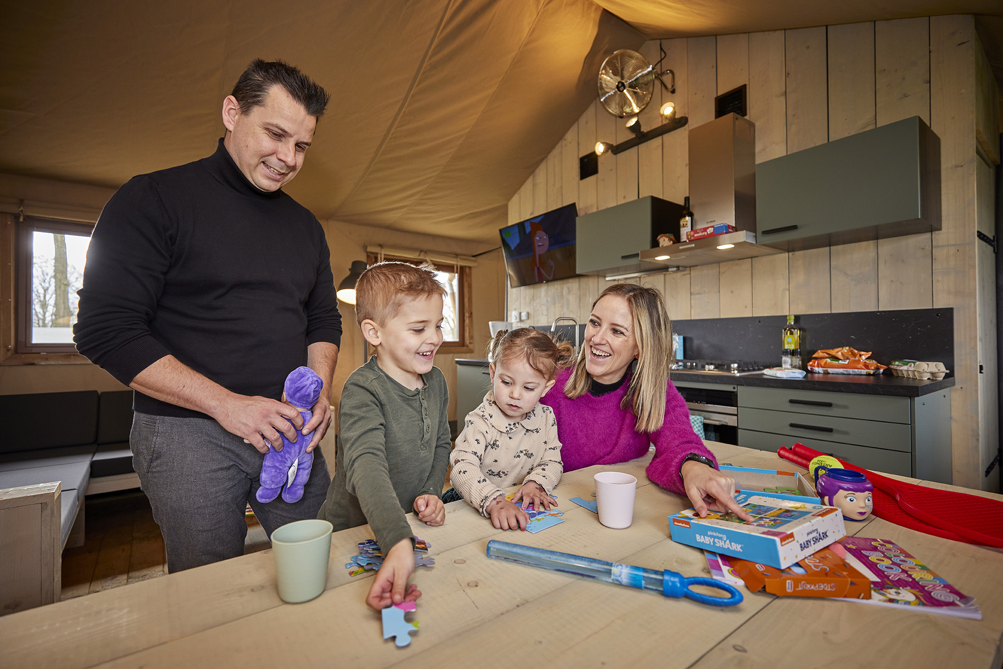 Familie speelt samen aan de eettafel in een safaritent in een ruime en luxe ingerichte safaritent op De Leistert.