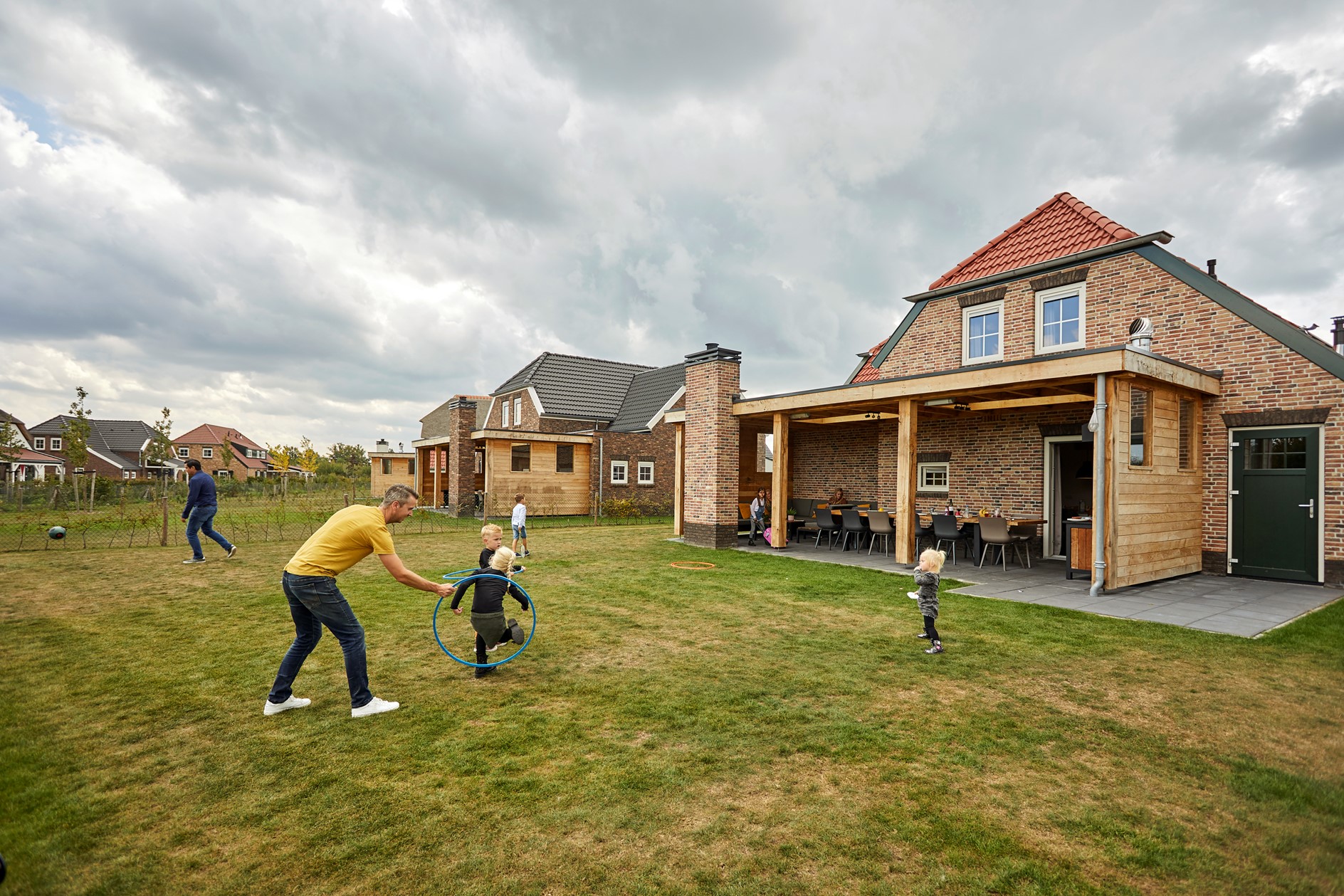 Een familie speelt met een hoepel op het grote grasveld achter hun luxe vakantieboerderij op Recreatiepark De Leistert.
