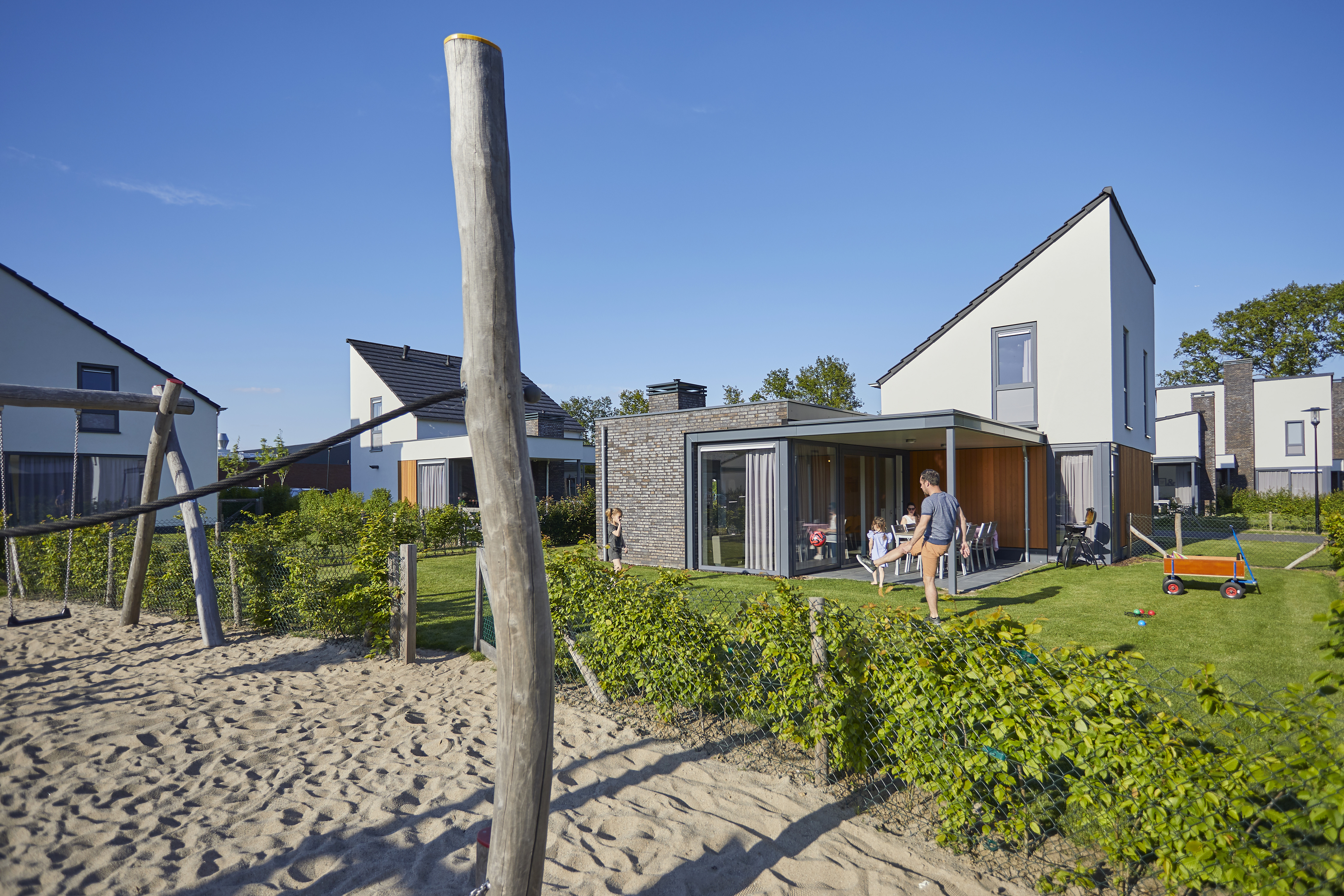 Moderne vakantiehuizen op Recreatiepark De Leistert met een centrale zandspeeltuin direct voor de terrassen.