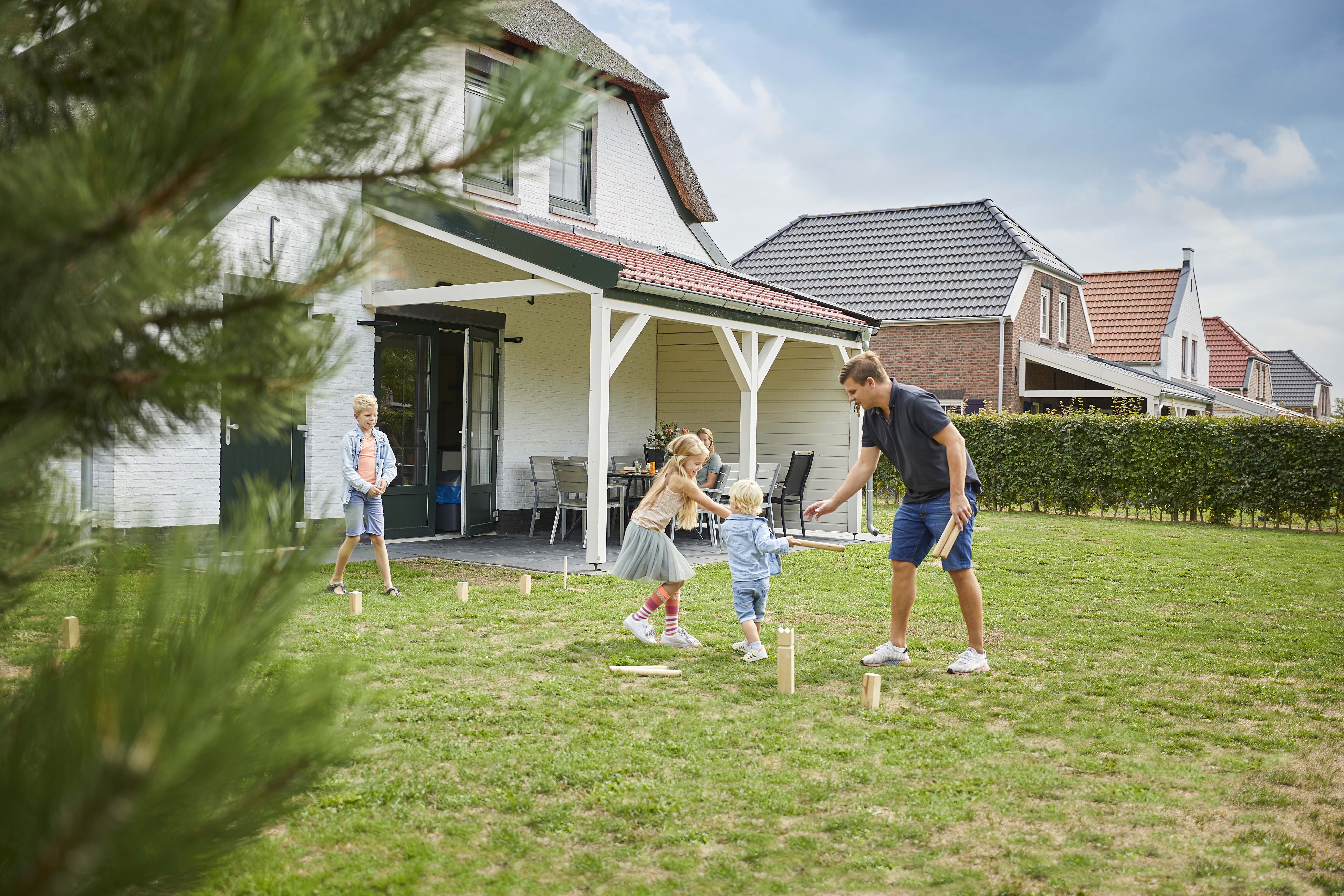 Een familie speelt het populaire werpspel Kubb op het grasveld in de tuin van hun vakantiehuis op Recreatiepark De Leistert.