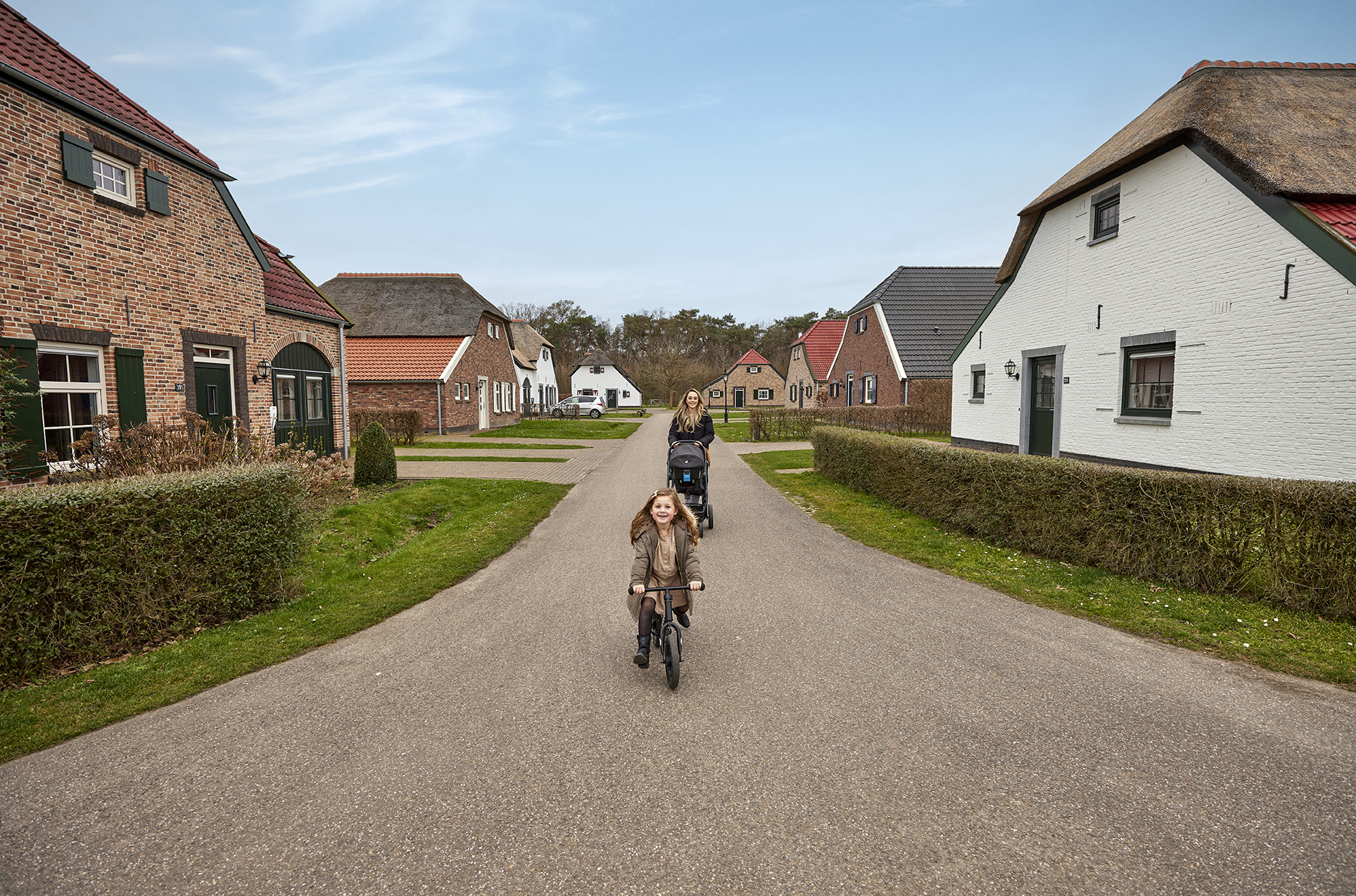 Moeder en klein meisje op een fiets lopen een rondje over het vakantiepark.