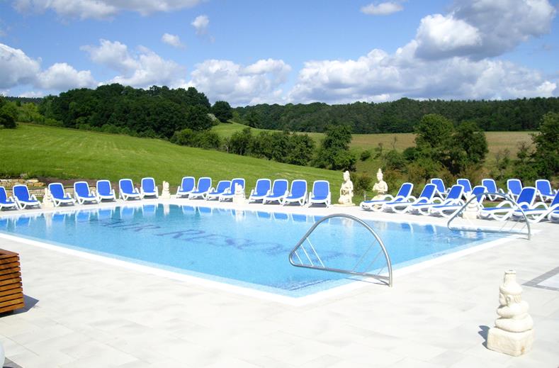 Het zonnige buitenzwembad van het FAIR Resort, omgeven door groene heuvels in de natuur van Thüringen.