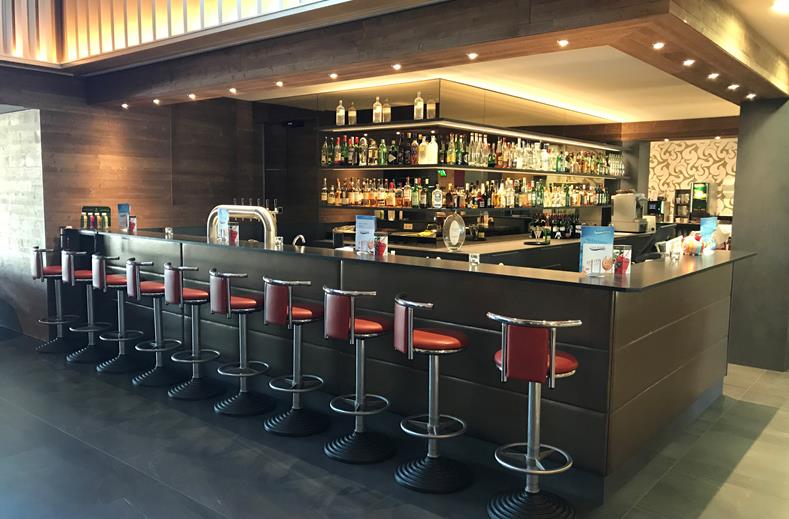 De sfeervol verlichte hotelbar van het FAIR Resort met comfortabele barkrukken, ideaal voor een drankje in de avond.