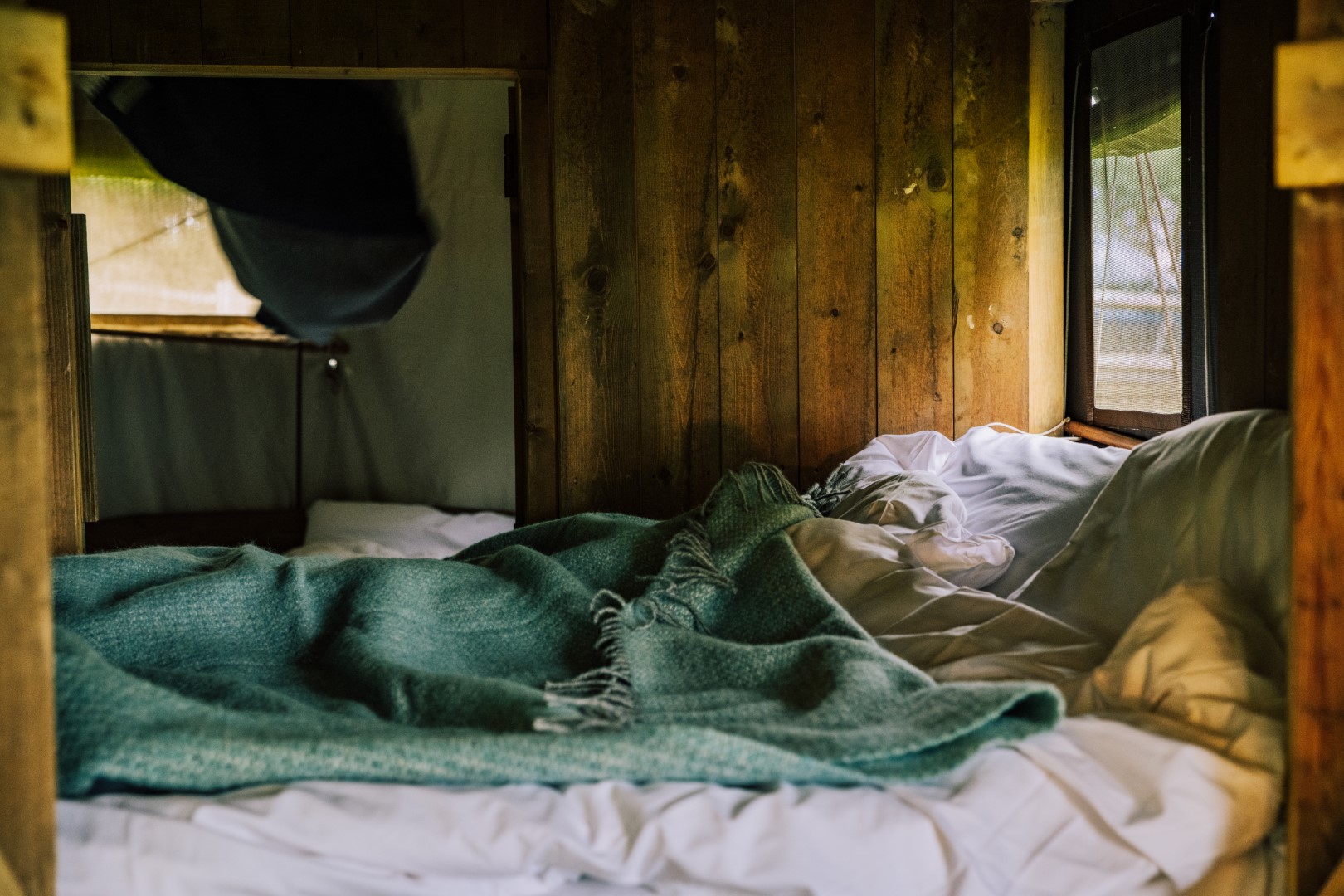 Comfortabel bed met zachte dekens en houten wanden in de glamping accommodatie van Hilserhof, voor een heerlijke nachtrust.