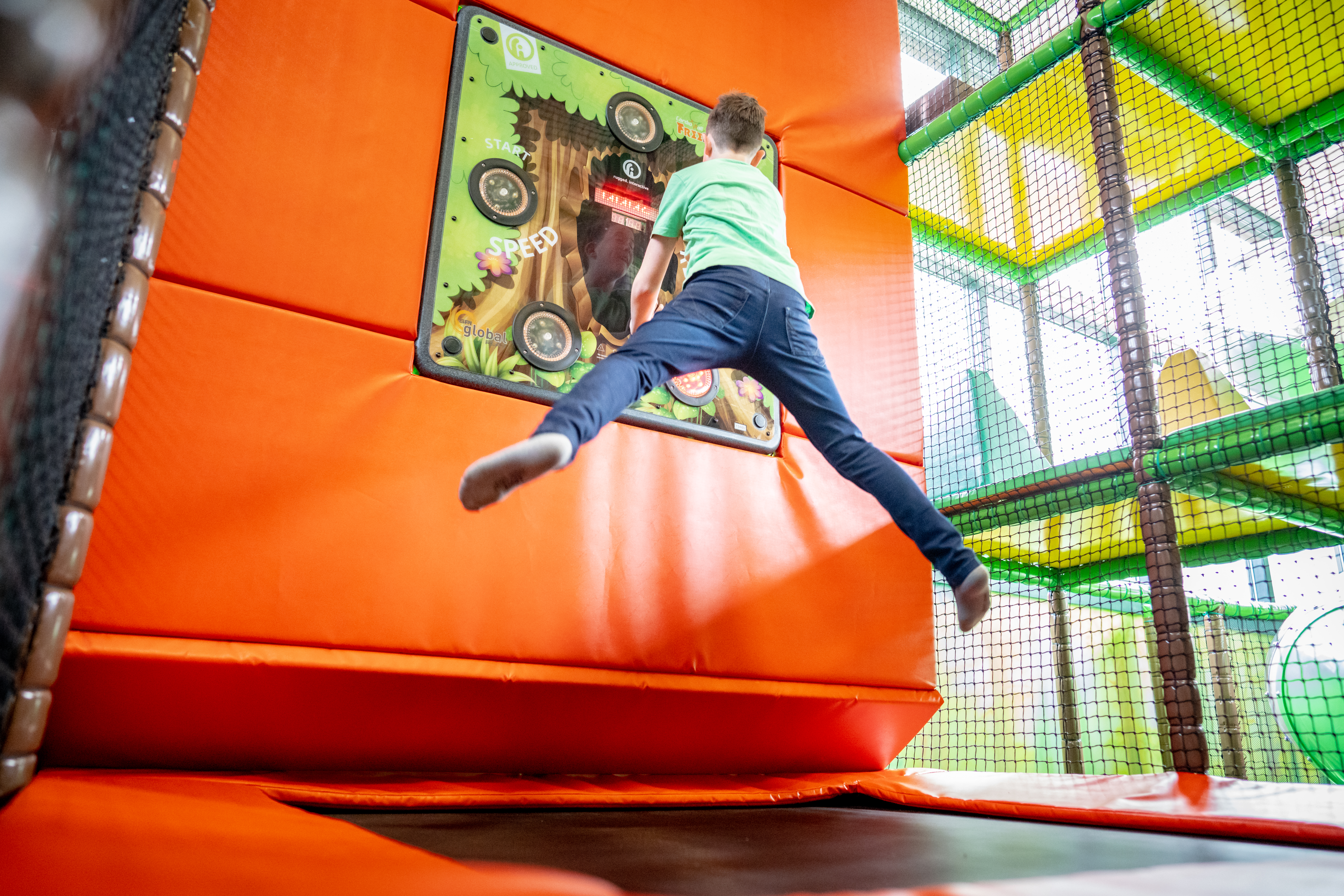 Jongen springt hoog in de lucht op de indoor trampoline in het kleurrijke indoorspeelparadijs van het vakantiepark Landal De Lommerbergen in Limburg.