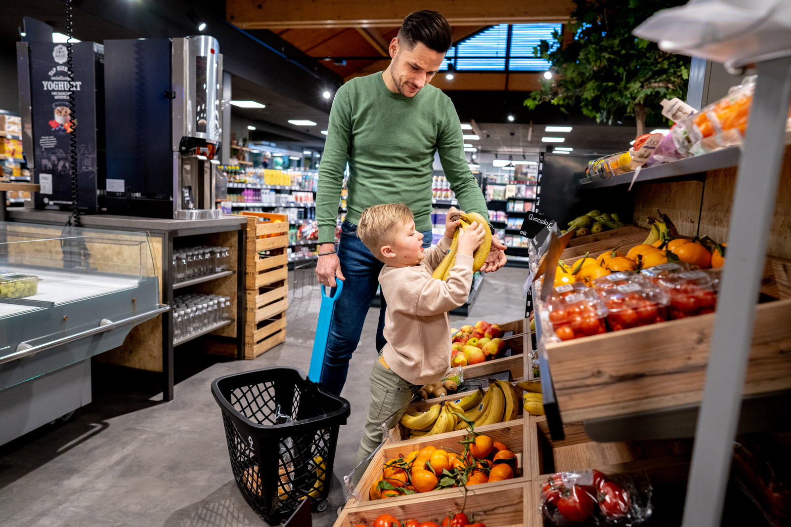 Vader en zoon doen samen boodschappen in de parkwinkel van Landal De Lommerbergen en kiezen vers fruit uit voor het ontbijt.