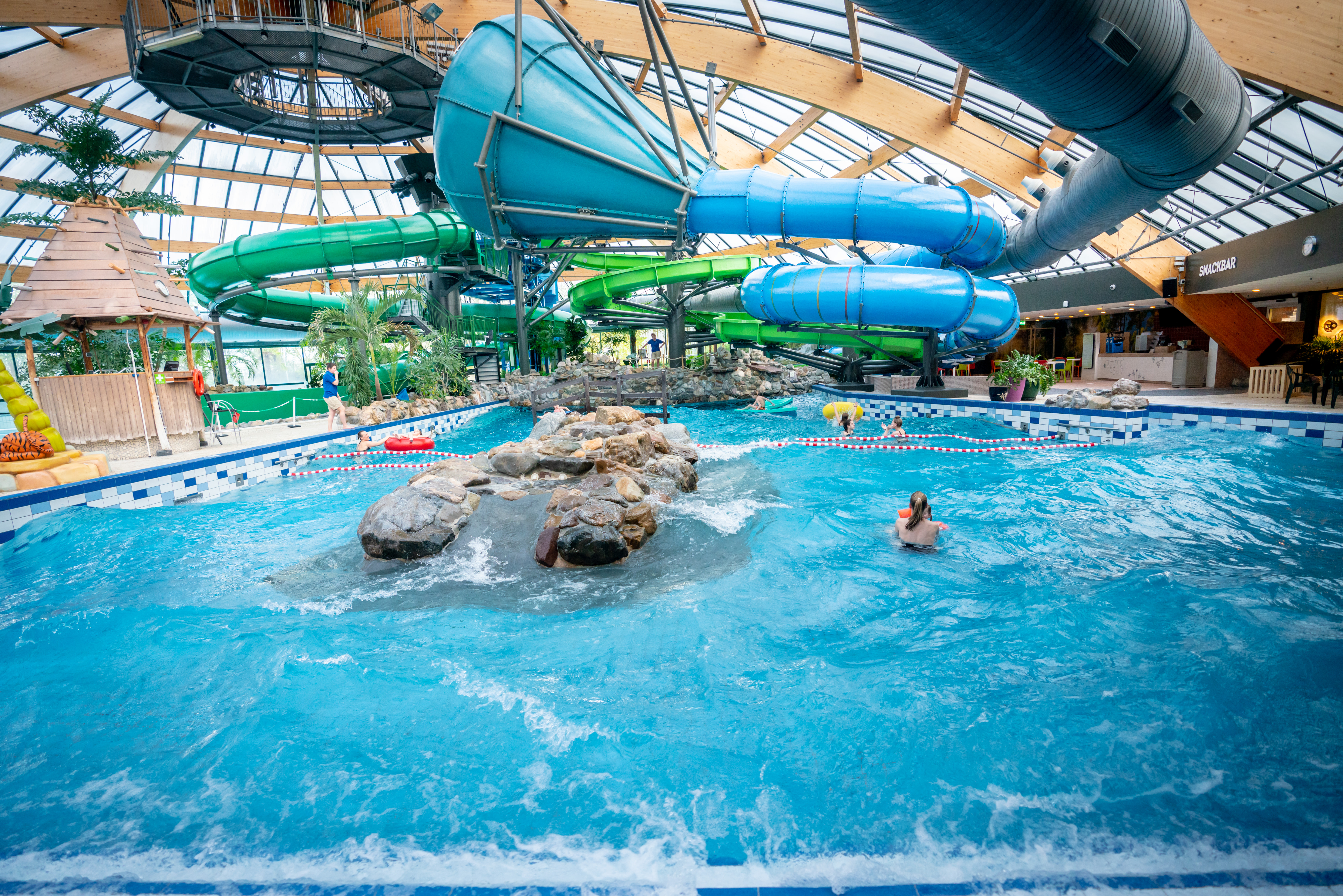 Het golfslagbad in het subtropische zwemparadijs van Landal De Lommerbergen, met op de achtergrond de vele spectaculaire waterglijbanen.