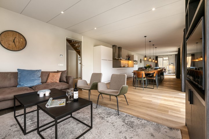 De moderne en sfeervolle inrichting van de woonkamer en keuken in een luxe vakantiewoning op Landal De Wedderplassen.