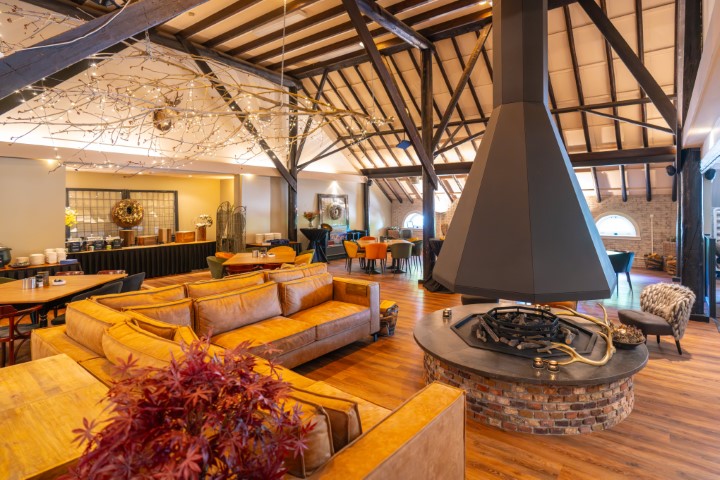 Het sfeervolle interieur van het restaurant op Landal De Wedderplassen, met een grote open haard in het midden.