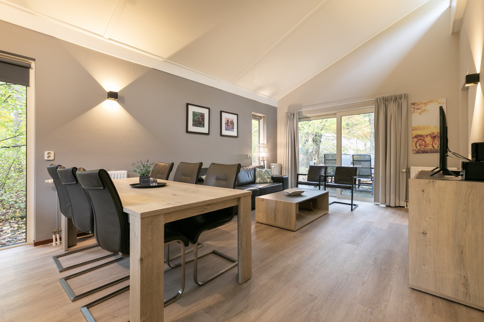 Ruime en lichte woonkamer met een grote eettafel en een comfortabele zithoek in een bungalow op Parc de Berkenhorst.