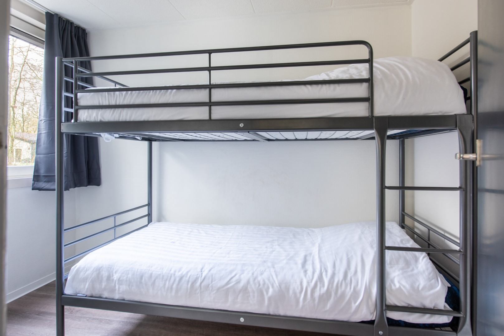 Een kinderslaapkamer met een modern, zwart metalen stapelbed in een vakantiehuis op Parc de Berkenhorst.