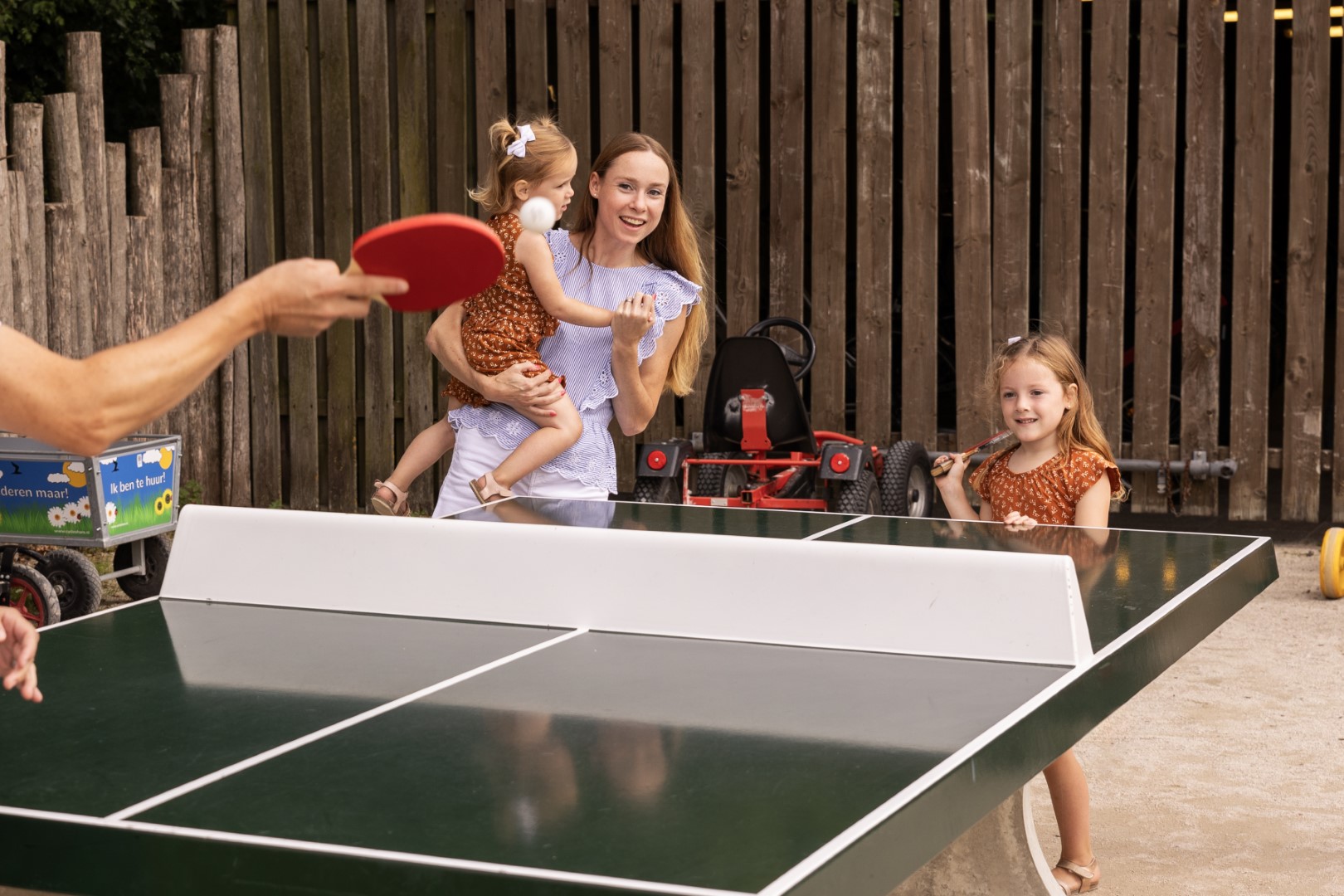 Een gezin speelt samen een potje tafeltennis bij een outdoor pingpongtafel op Vakantiepark Port Greve.