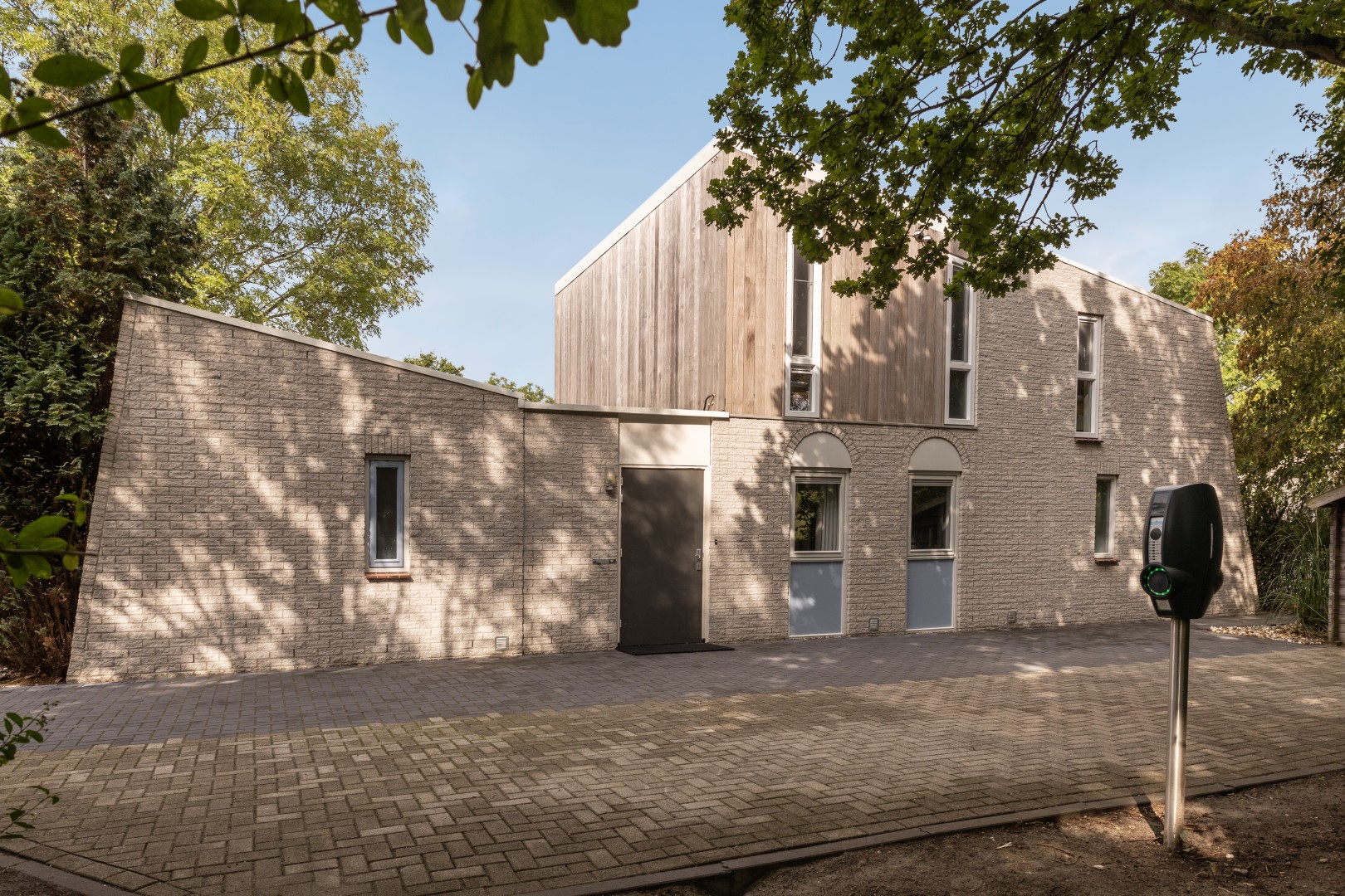 De moderne buitenkant van een nieuw vakantiehuis op Vakantiepark Port Greve in Zeeland, met een eigen laadpaal voor elektrische auto's.