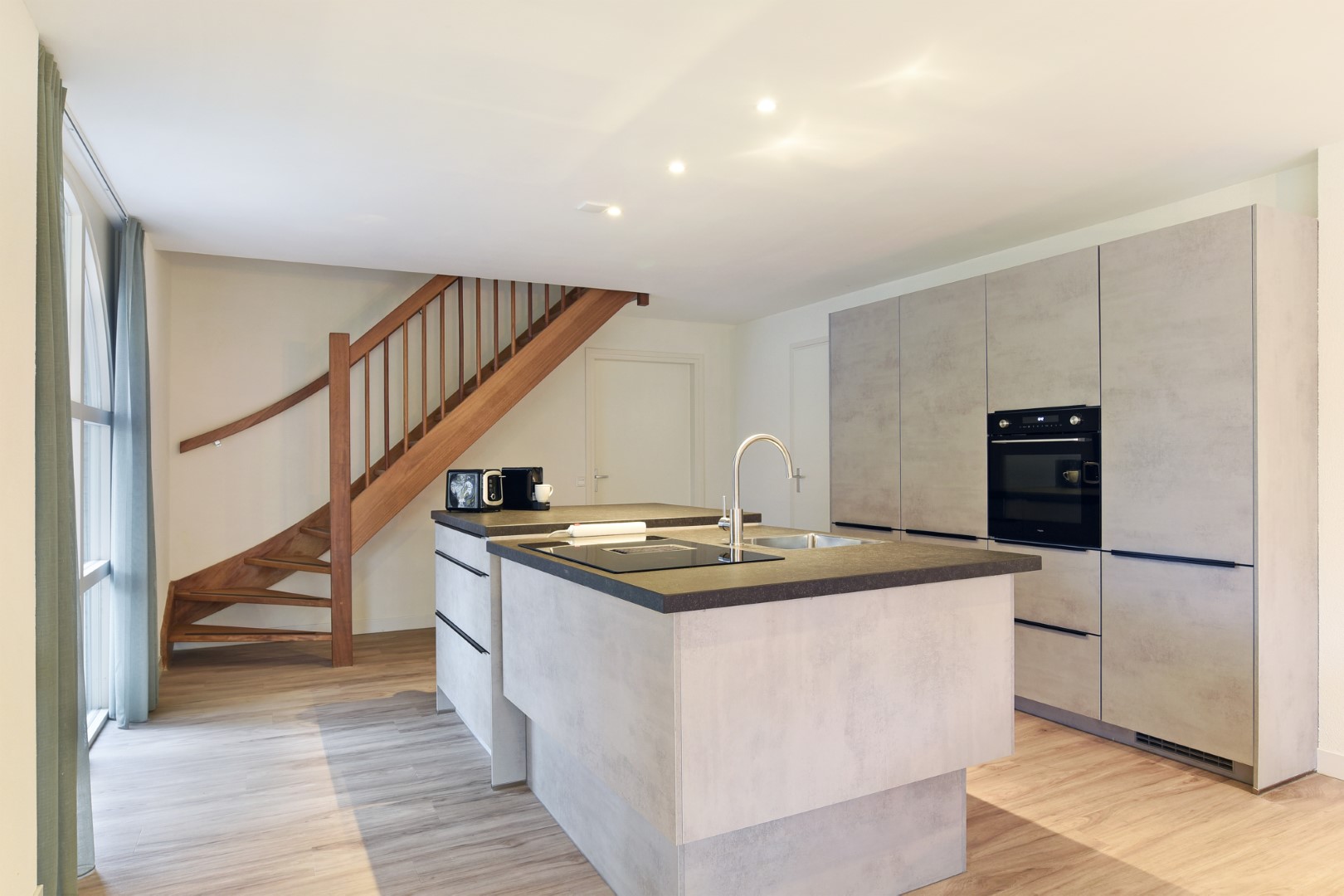 De moderne open keuken met een kookeiland en inbouwapparatuur in een luxe vakantiewoning op Port Greve.