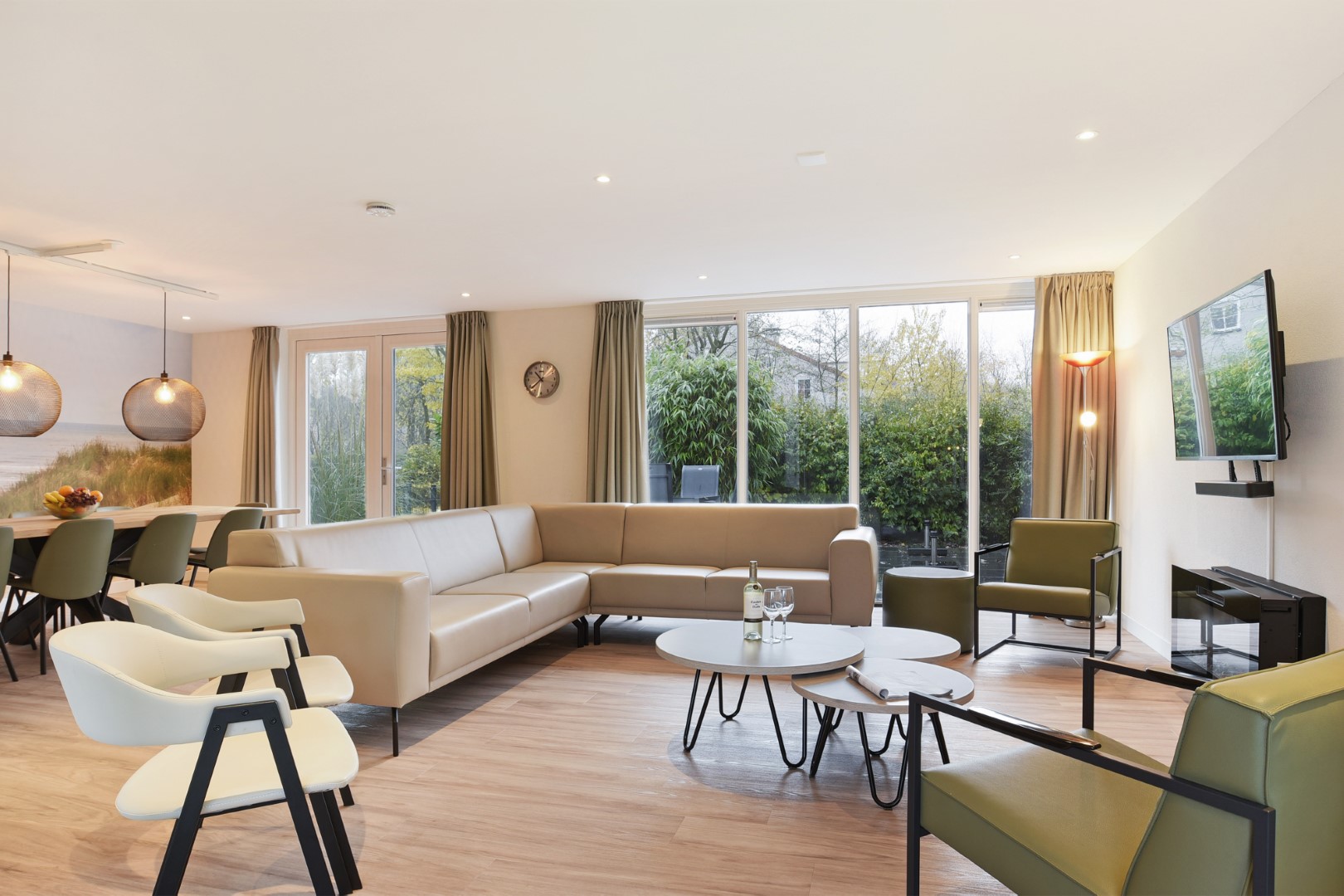 De ruime, licht ingerichte woonkamer van een vakantiehuis op Port Greve met een grote hoekbank, eettafel en uitzicht op de tuin.