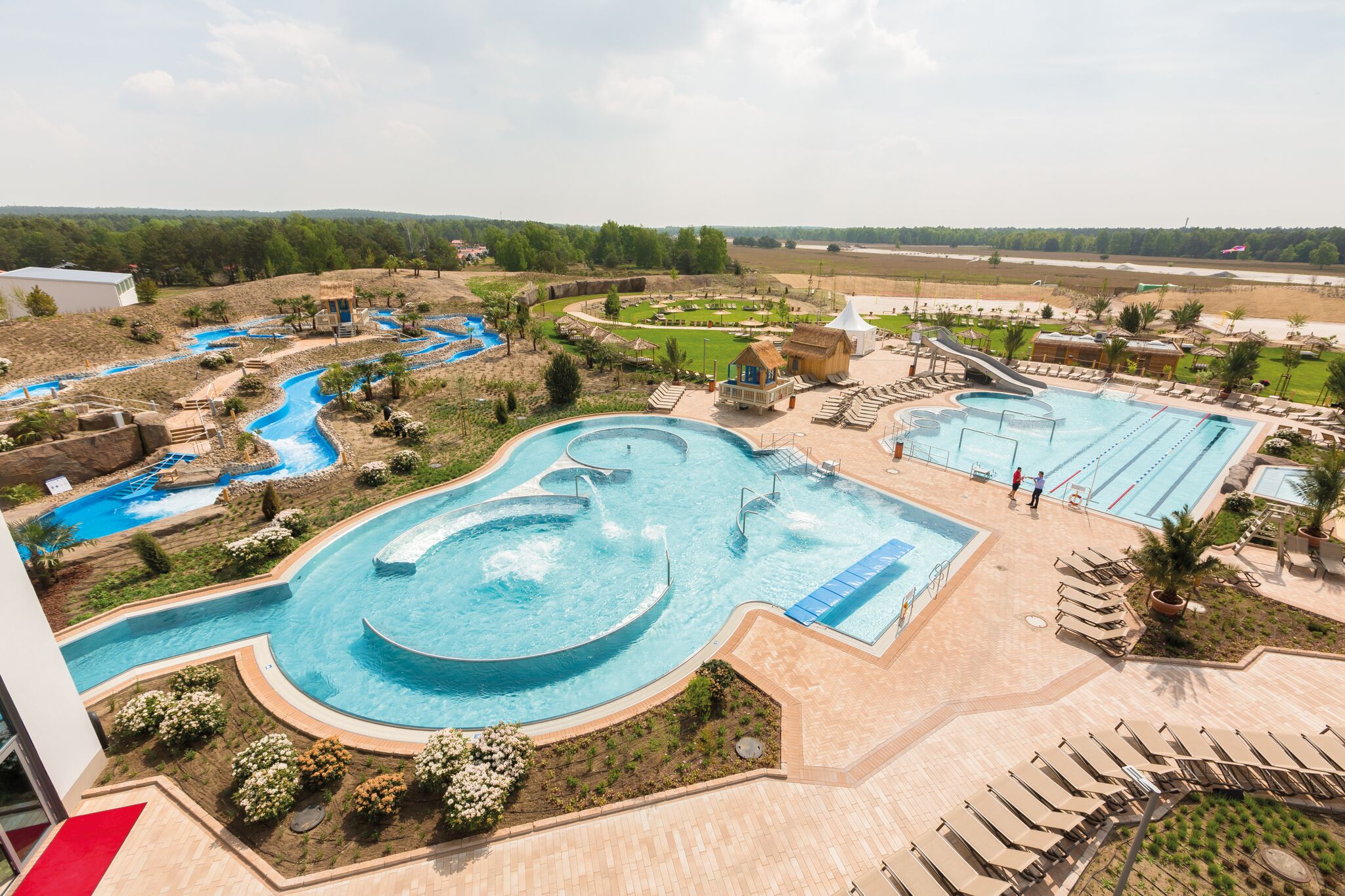 Luchtfoto van de waterspeeltuin in het buitengedeelte AMAZONIA van Tropical Islands, met ondiepe baden, fonteinen en speeltoestellen voor jonge kinderen.