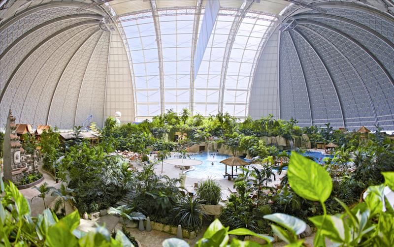 Weids overzicht van het immense indoor regenwoud in Tropical Islands, met duizenden tropische planten en bomen onder de gigantische koepel.