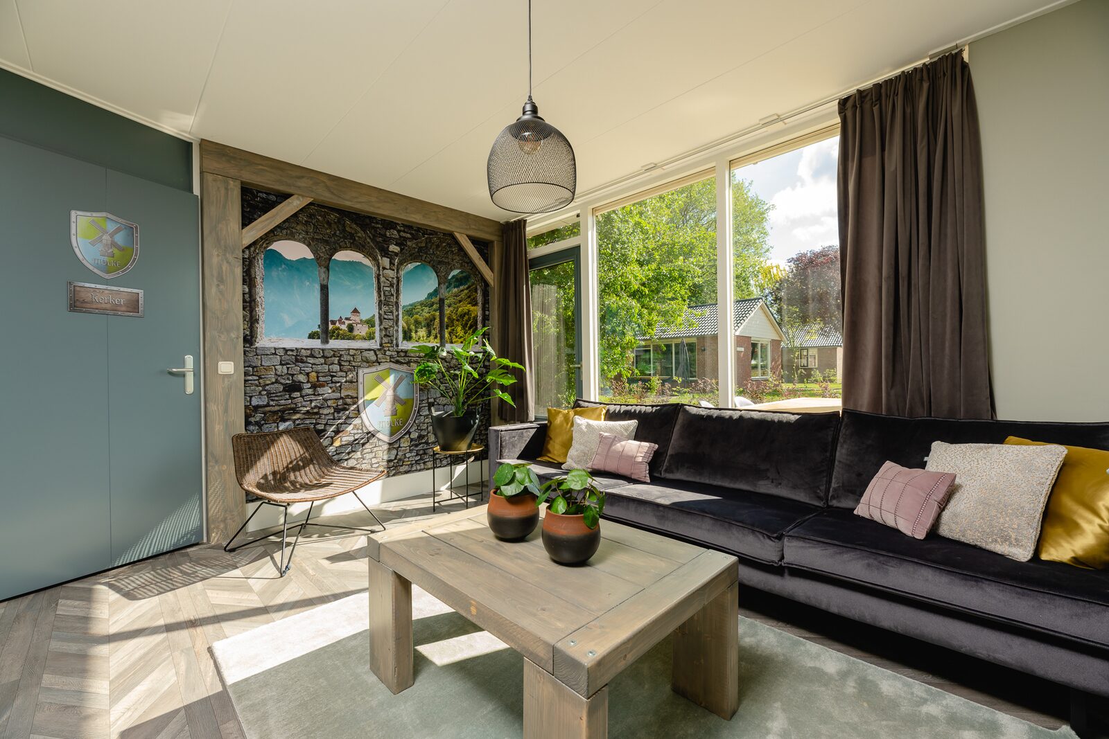 De sfeervolle woonkamer van een Reggehooiberg op Vakantiepark Molke, met een grote hoekbank en uitzicht naar buiten.
