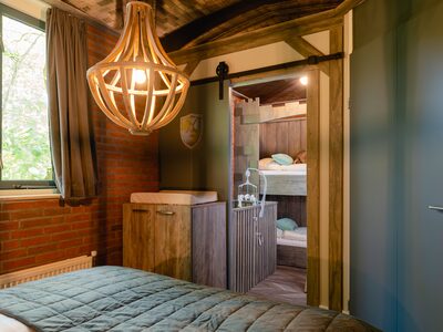 Het sfeervolle, houten interieur van de boomhut op Vakantiepark Molke, met een doorkijkje naar de knusse bedstee voor de kinderen.