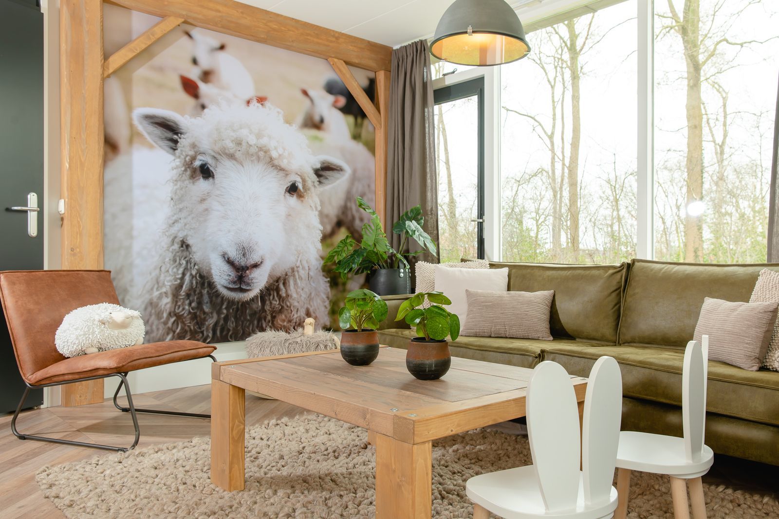 De gezellige woonkamer van een Boerderij-lodge op Vakantiepark Molke, met een grote fotowand van een schaap.
