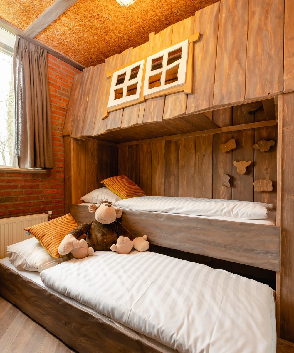 Een knus houten stapelbed in een boomhut op Vakantiepark Molke, met een aap-knuffel op het onderste bed.