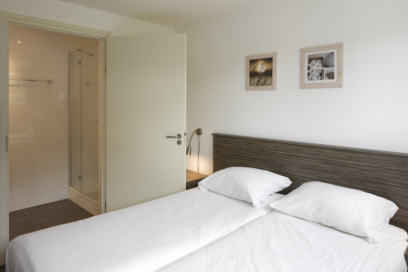 Comfortabele slaapkamer met een opgemaakt tweepersoonsbed en een eigen en-suite badkamer op Waterpark Zwartkruis.