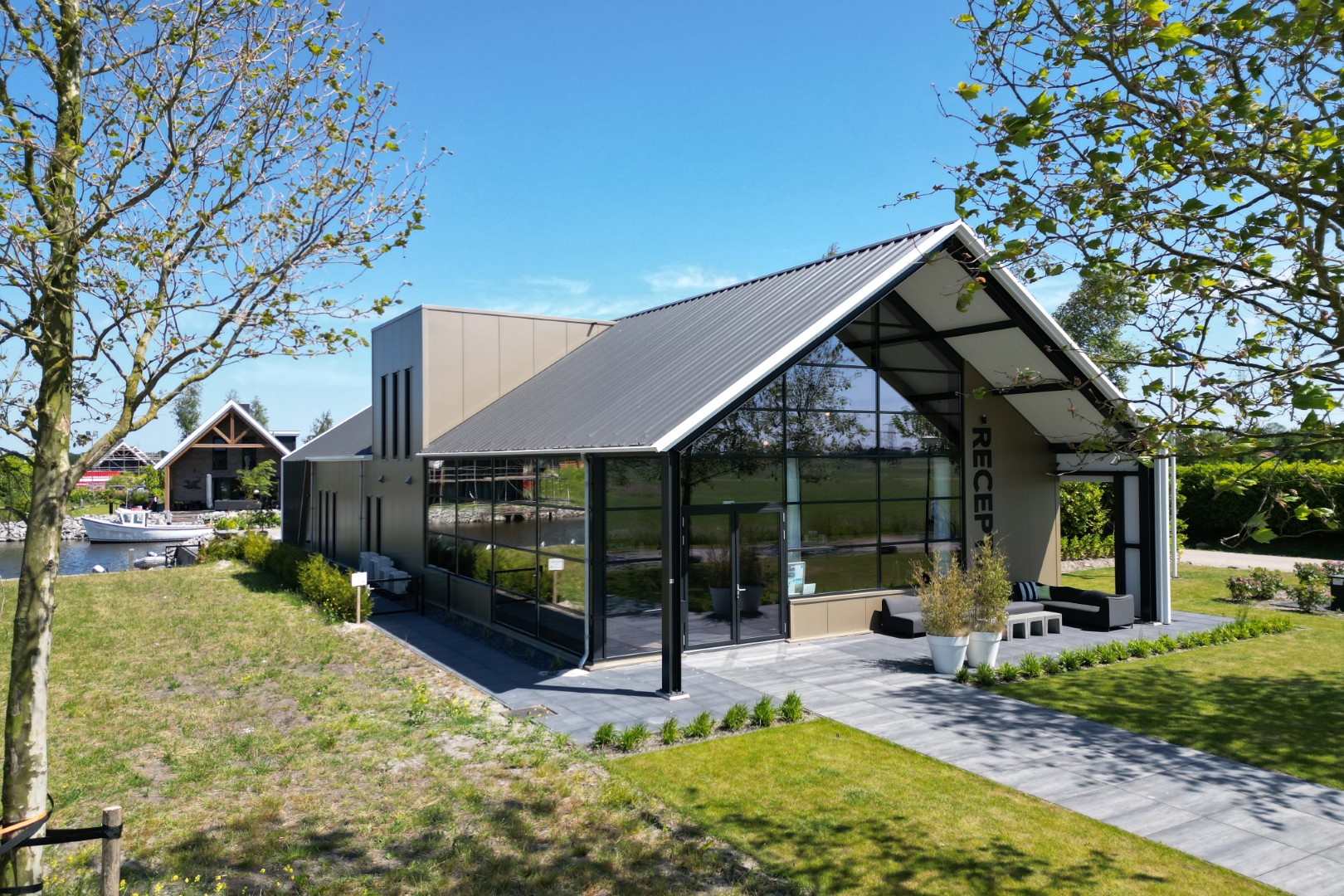 Het moderne, architectonische hoofdgebouw van Waterpark Zwartkruis met grote glazen pui, gelegen aan het water.